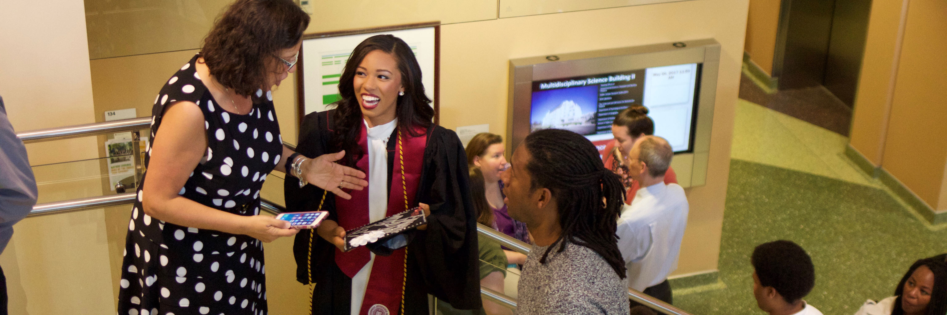 teacher talking with graduated student in cap and gown