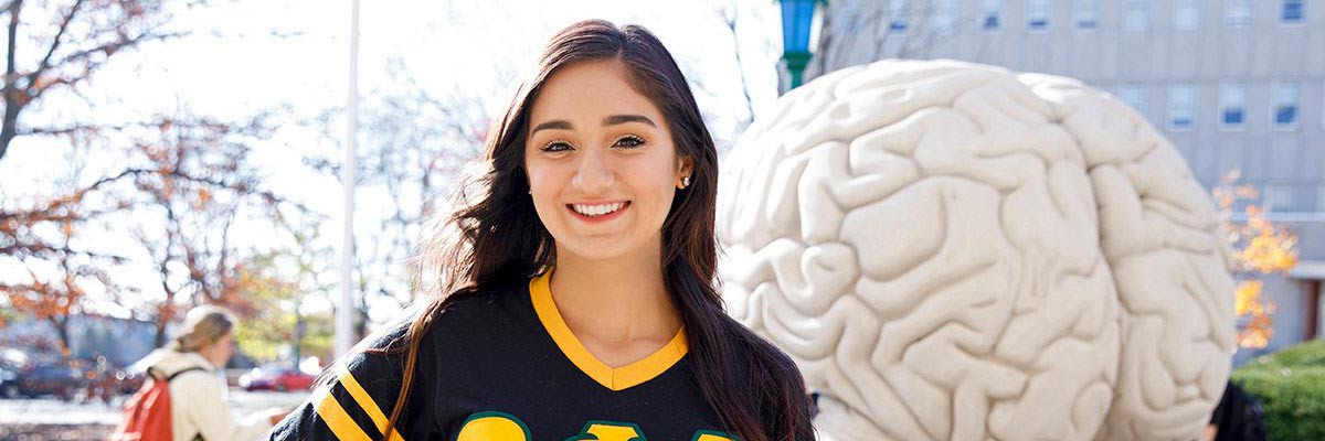 Smiling student standing in front of the human brain statue