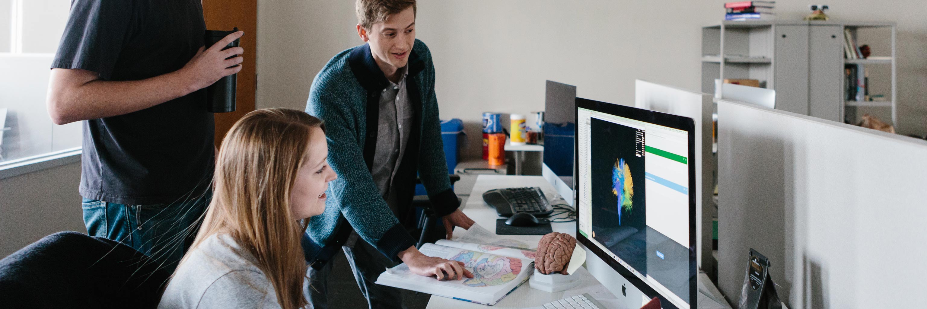 three students gather around a computer