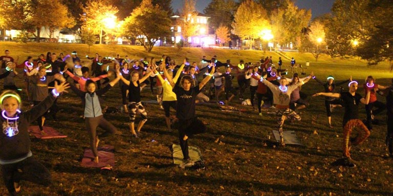 students doing yoga at night wearing glow stick necklaces