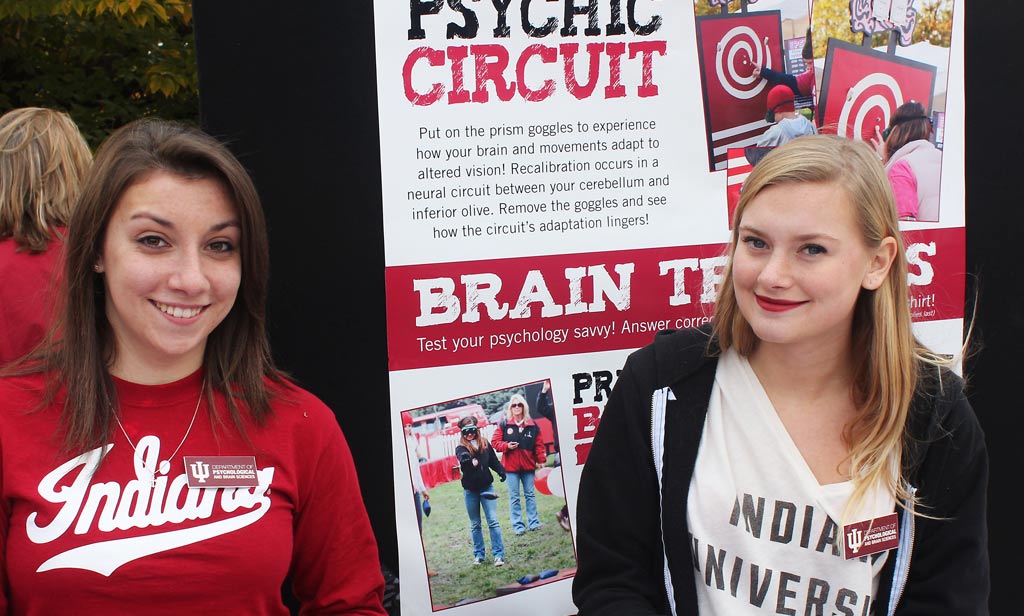 two women standing in front of poster, smiling at camera