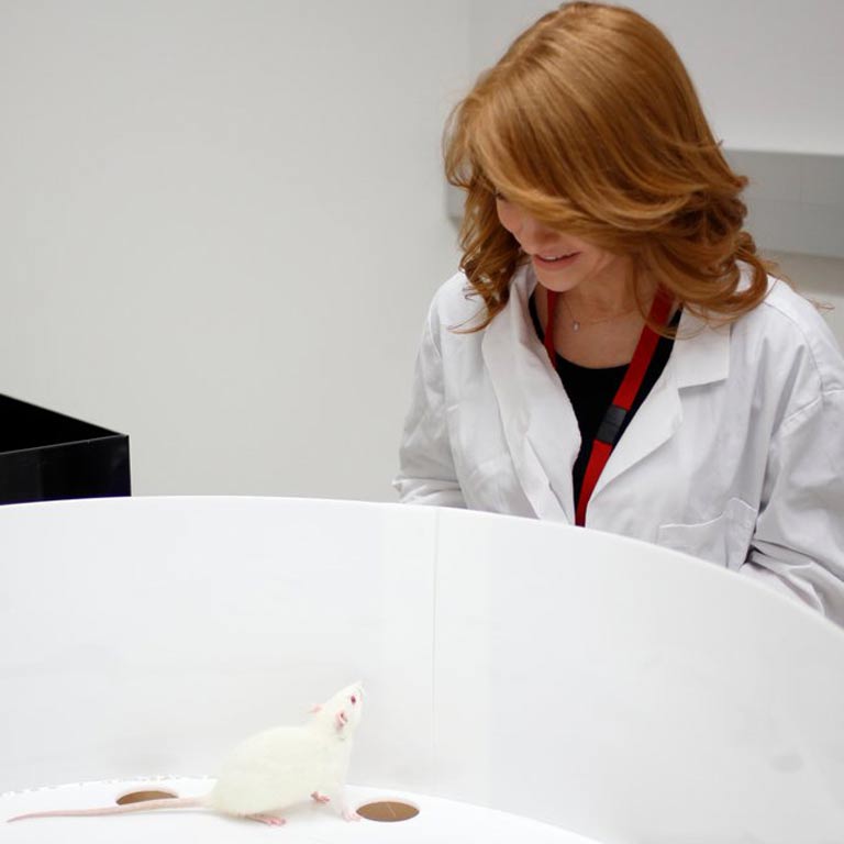 smiling woman wearing a lab white coat