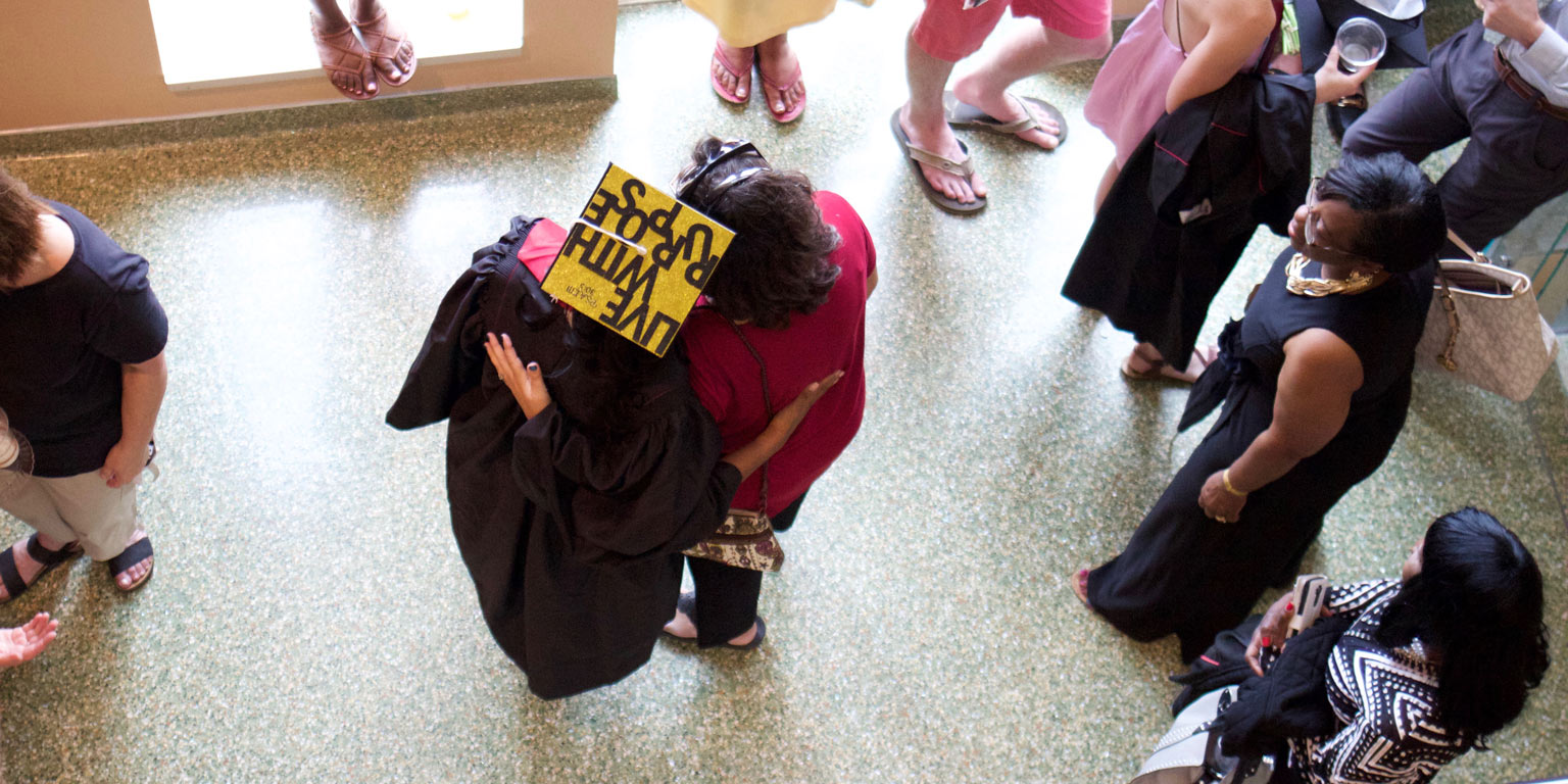 family member embraces graduated student in cap and gown